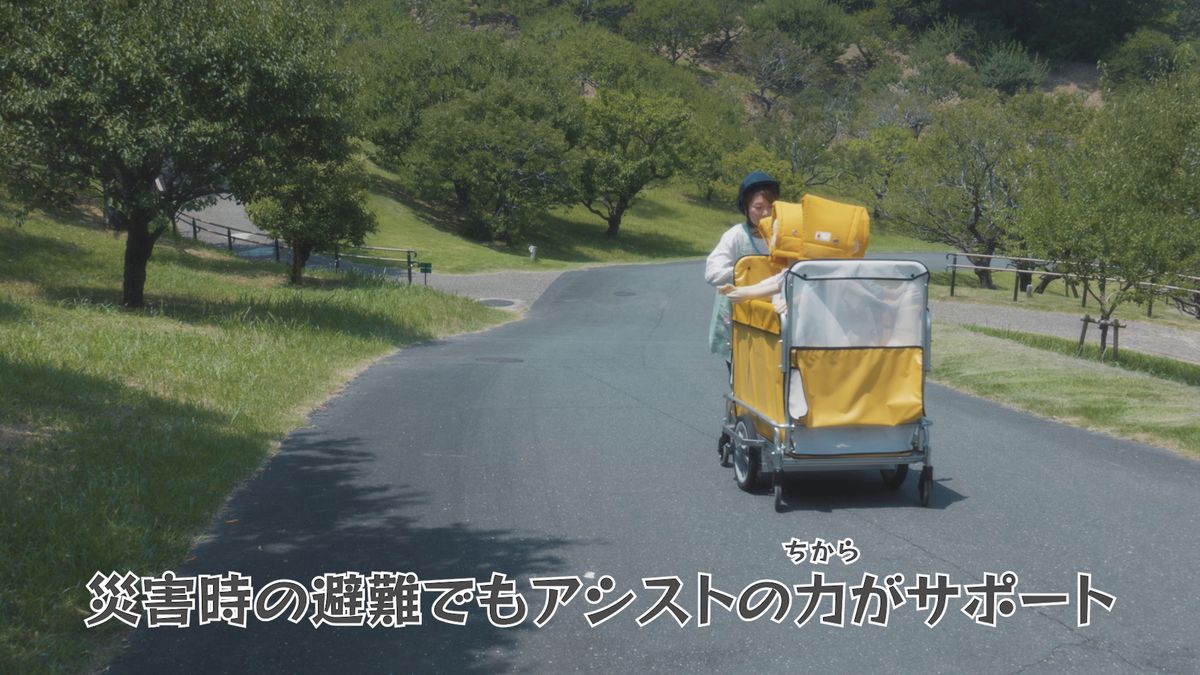 ヘルメットをかぶった保育士が避難訓練でてくてくスワニーを押している様子